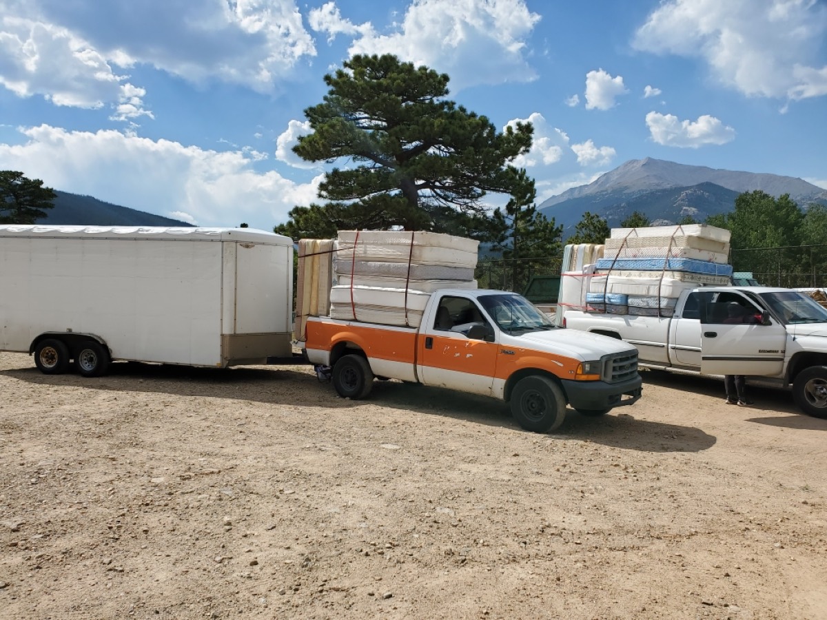 Pickup trucks and a trailer loaded with mattresses on a recycling run