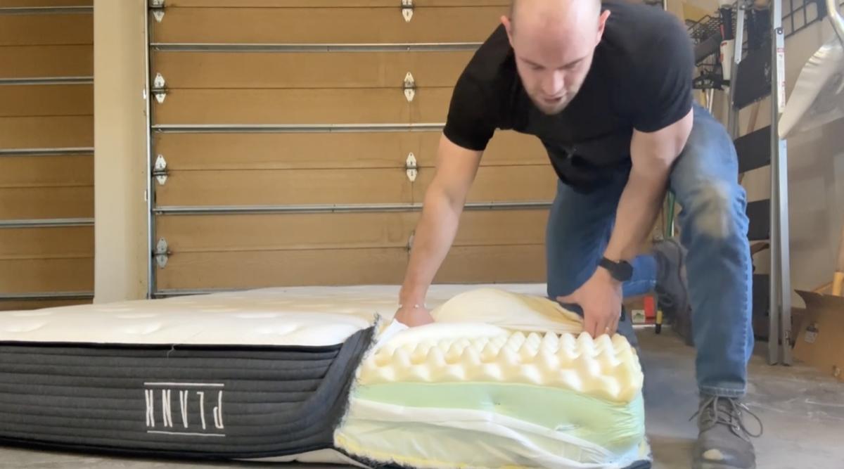 Tearing open Plank mattress to show layers